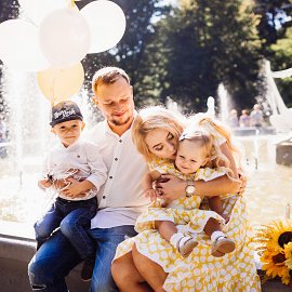 lovely-family-dressed-same-clothes-sits-fountain-with-their-children-yellow-balloons