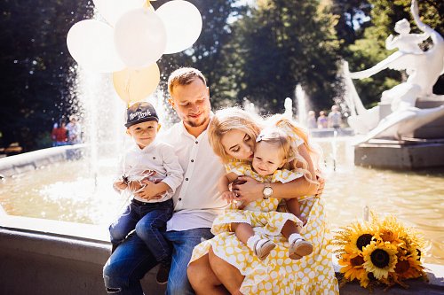 lovely-family-dressed-same-clothes-sits-fountain-with-their-children-yellow-balloons